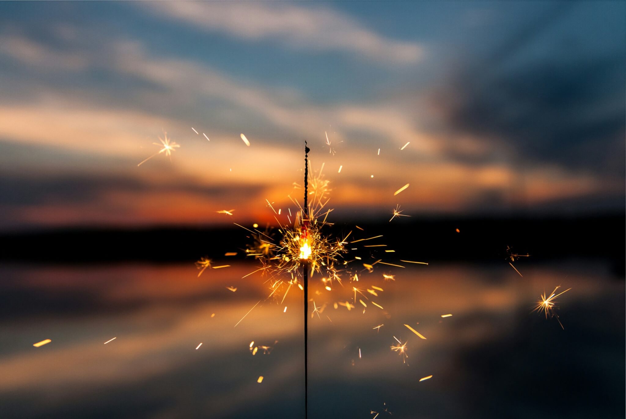 A sparkler burning a sunset in the background