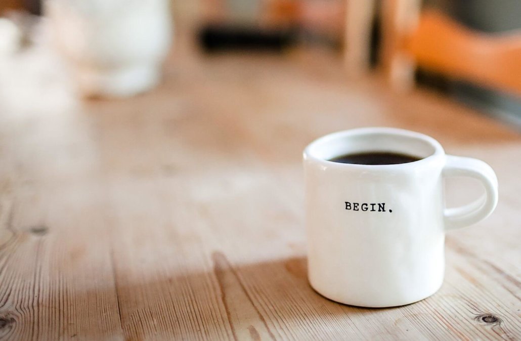 White mug filled with coffee. The text on the mug reads 