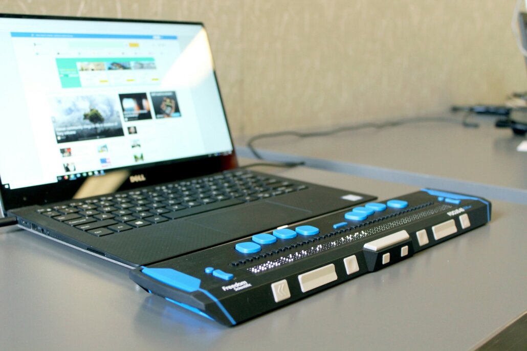 a laptop computer with a refreshable braille display sitting on top of a desk.