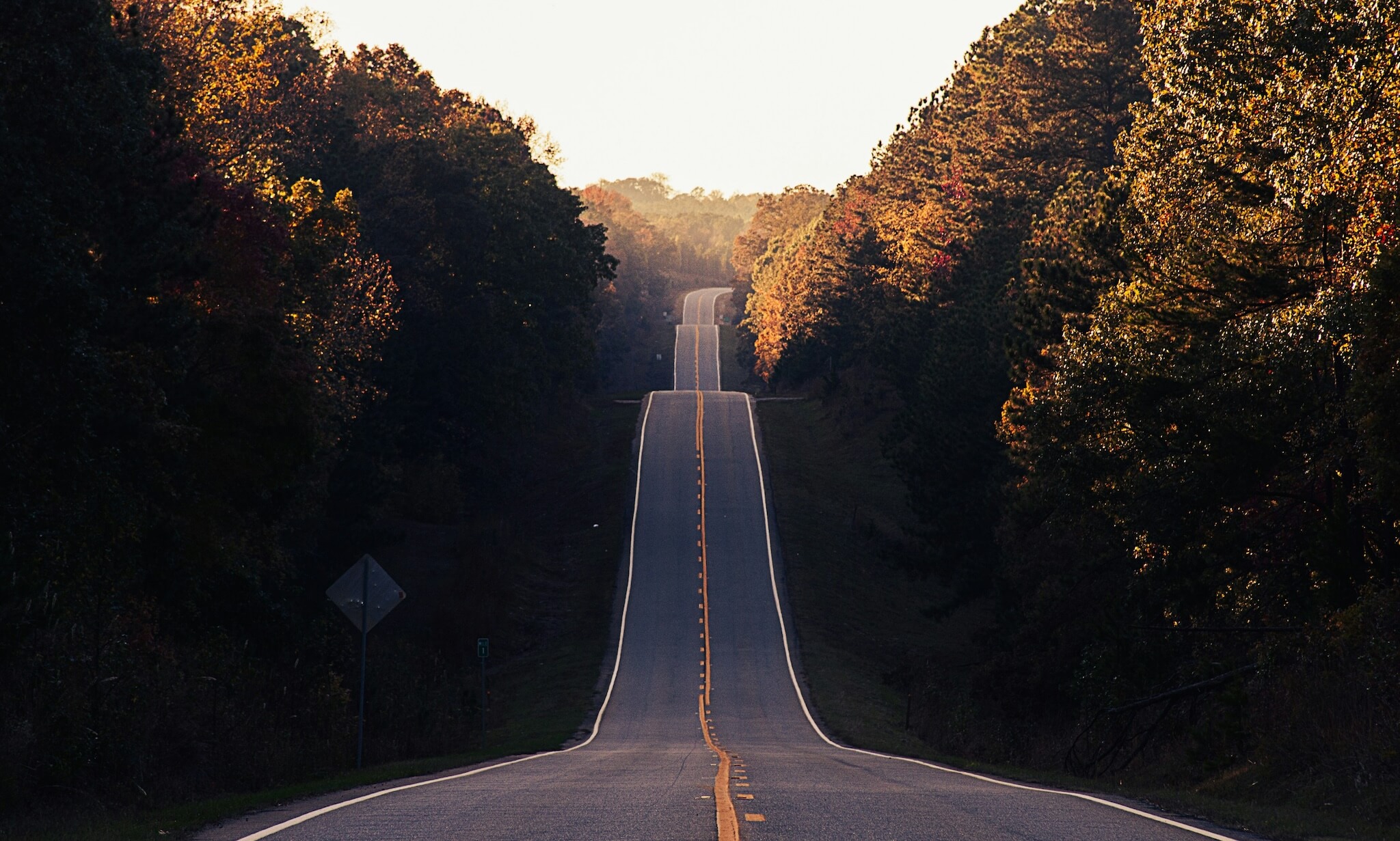 A highway cuts through a hilly landscape. It can be seen far into the distances, signalling a clear path ahead.