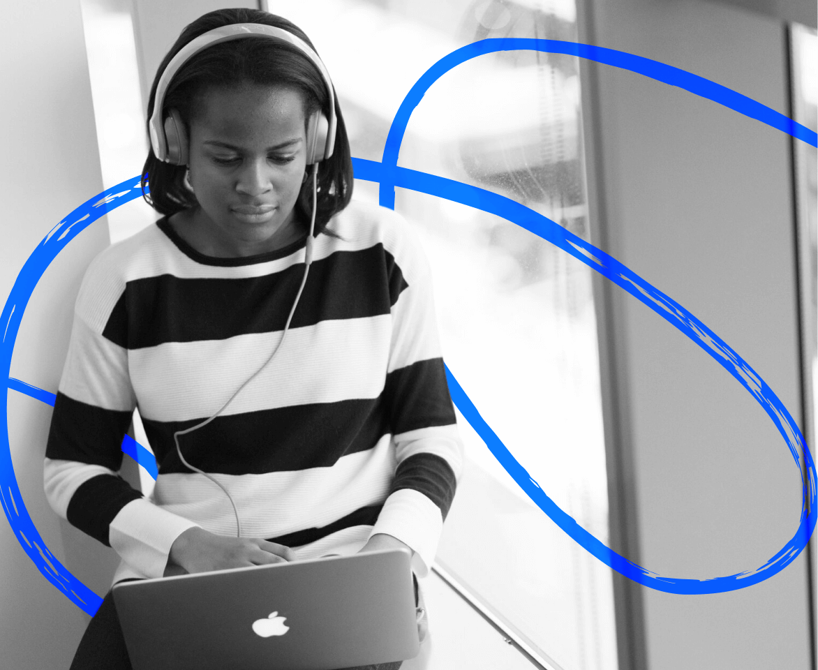 A young woman using a laptop and wearing headphones