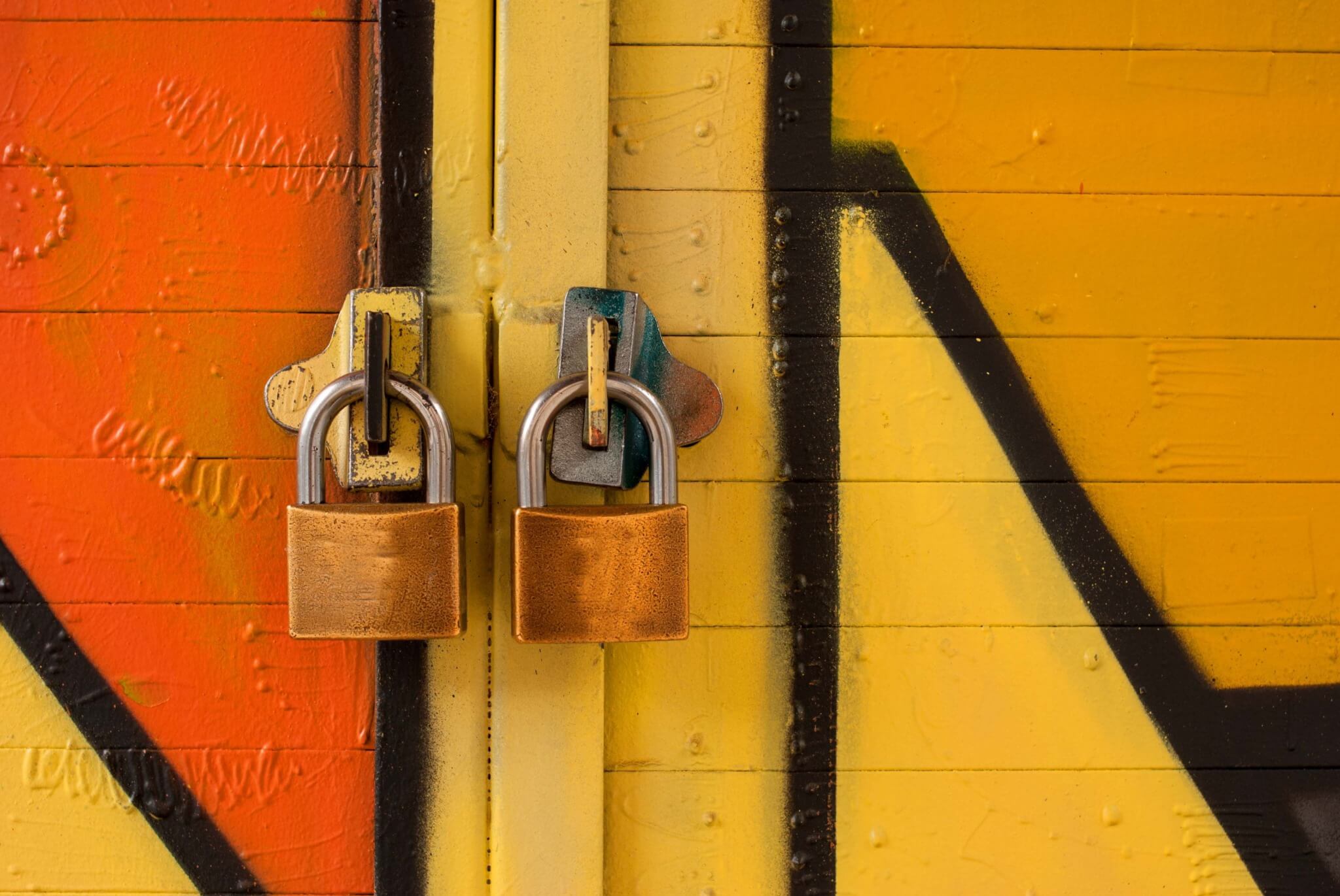 Two closed padlocks against a vibrant orange and yellow background